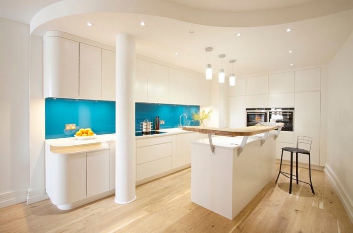 Безупречное сочетание - белая кухонная мебель с фартуком из стеклянных панелей яркого бирюзового цвета.