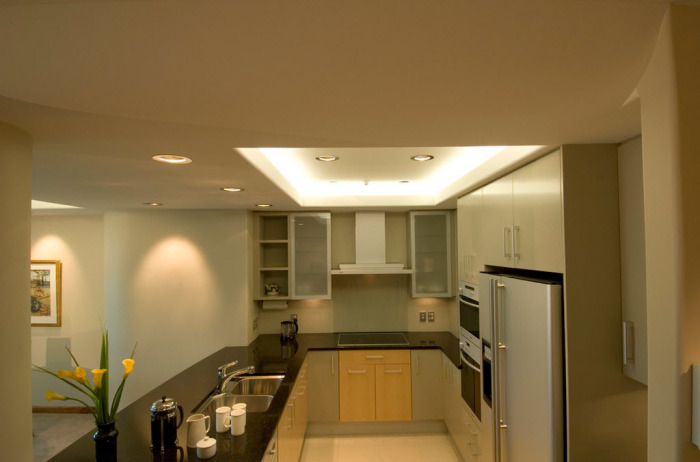 Визуально расширить помещение помогут точечные яркие светильники, расположенные по периметру потолка, а также над навесными шкафчиками и полочками.