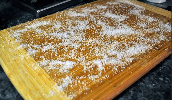 Посыпьте разделочную доску из дерева солью Посыпьте разделочную доску из дерева солью