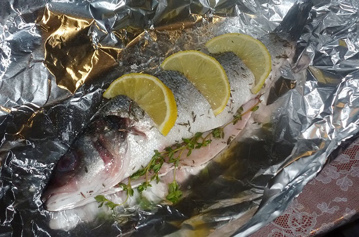 Положите лимон на рыбу и запечатайте в фольгу