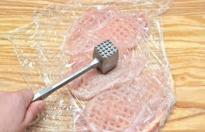 Заверните куриное филе в пленку и отбейте молотком