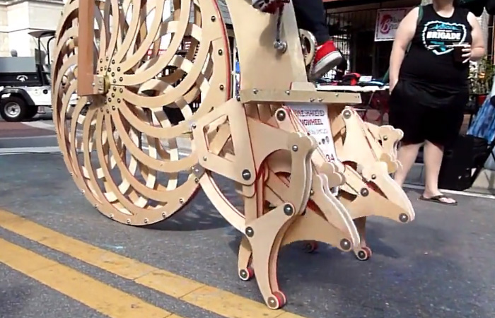 Гигантский деревянный велосипед-паук с ногами вместо заднего колеса.