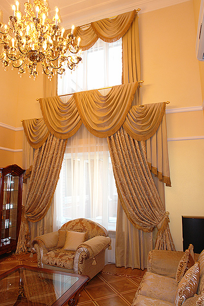 Шторы в интерьере гостиной, выполненной в классическом стиле. Исполнение в несколько уровней подчеркивает пространство и объем помещения.