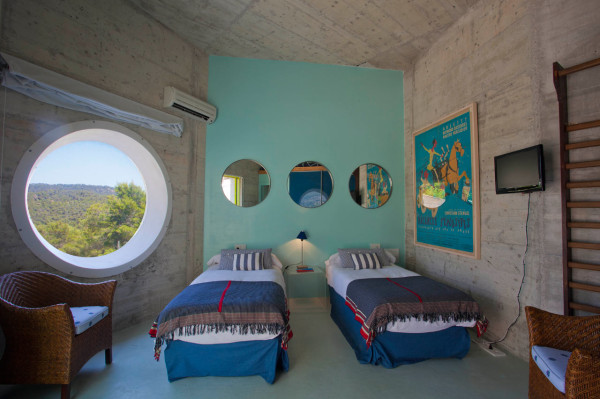 Комната с двумя одноместными кроватями и оригинальным окном в форме большого иллюминатора.