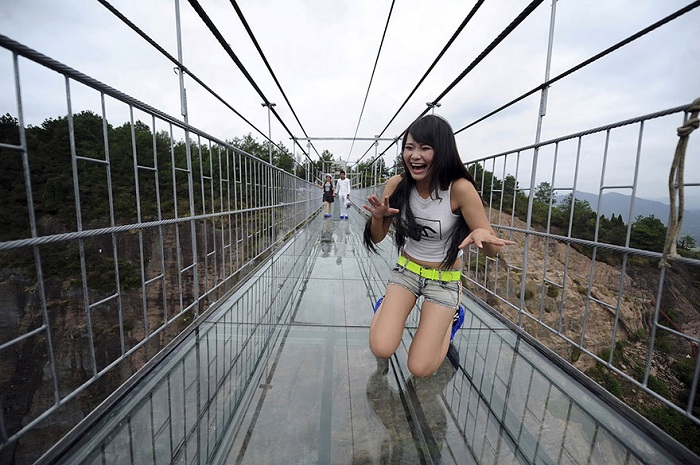 Испуганная туристка во время прохождения по стеклянному мосту.