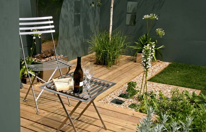 Хороший и нескучный вариант создать зону комфорта на веранде в окружении гармоничной садовой композиции.