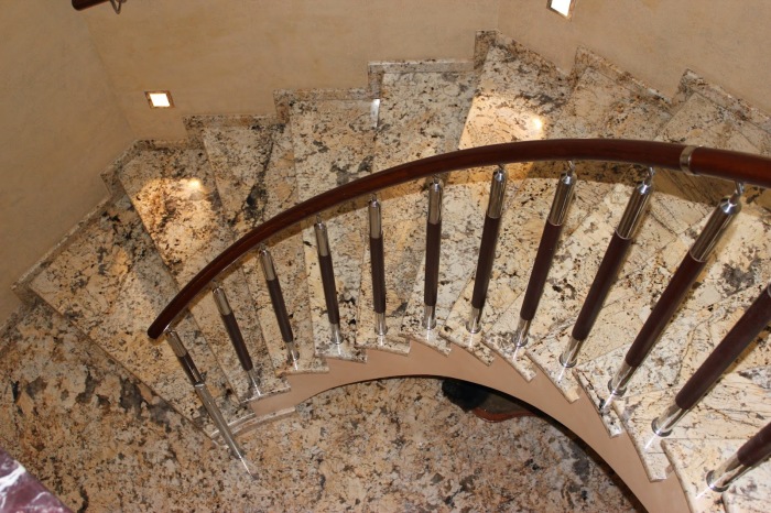 Эффектная спиральная лестница с металлическими перилами, выполненная из декоративного мрамора.