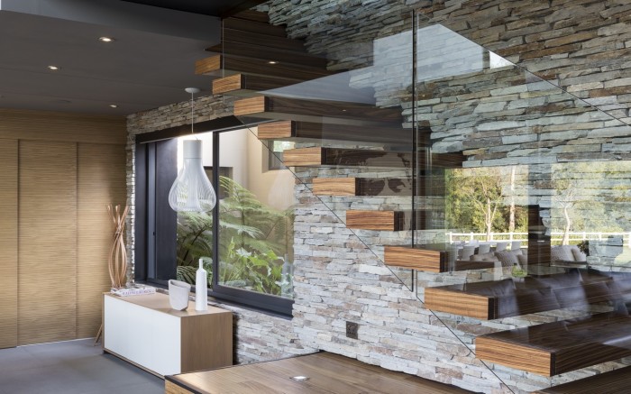 Лаконичный дизайн лестницы, сделанной из дерева, стекла и камня, гармонично вписался в интерьер дома.