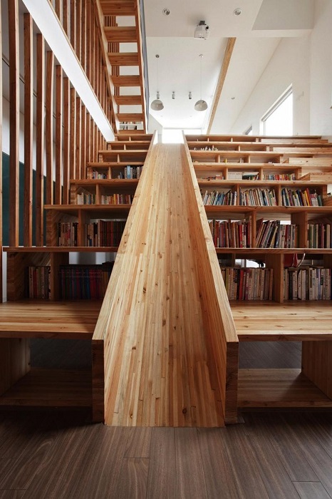 Необычная деревянная лестница со встроенными полками для книг и детской горкой.