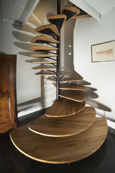 Роскошная винтовая лестница со ступенями оригинальной формы, выполненными из тёмной породы древесины.