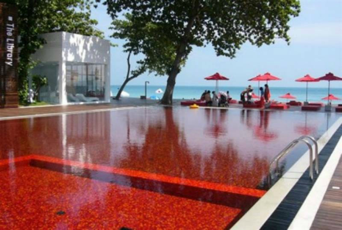 Яркий бассейн на пляже в Таиланде, вымощенный красной, желтой и оранжевой плиткой, что наполняет энергией всех, кто плавает в этом бассейне.