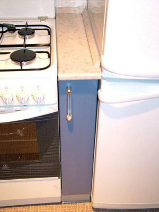Узкий шкафчик между плитой и холодильником.