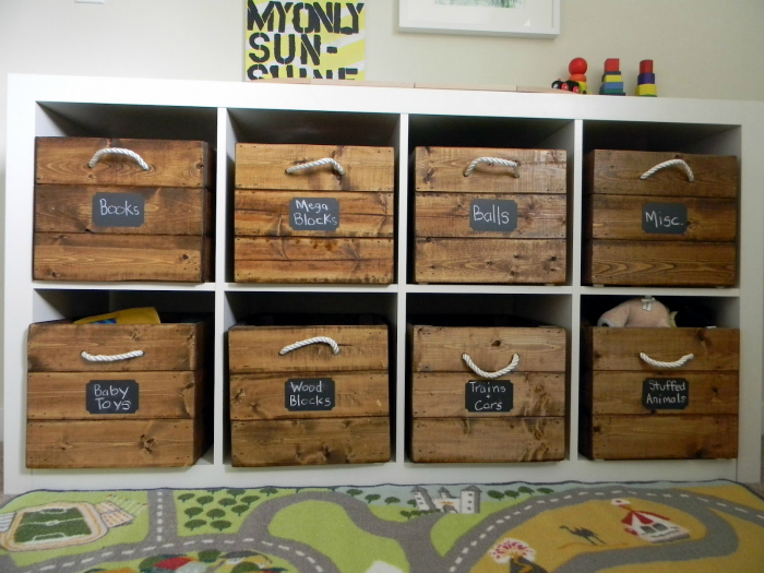 Маркированные деревянные контейнеры для упорядоченного хранения детских игрушек.