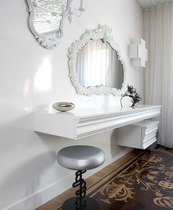 Белоснежный столик- полочка с зеркалом причудливой формы, украшенным потрясающей лепкой.