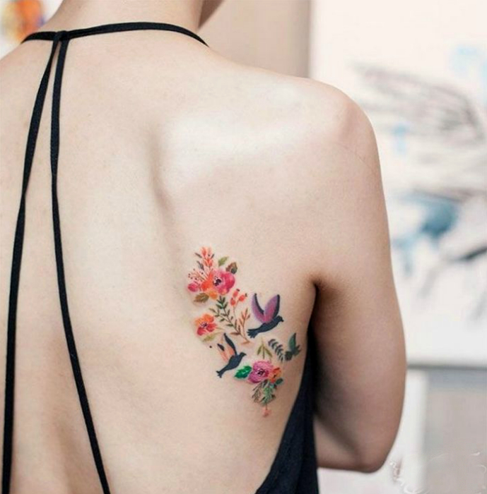 Татуировка с изображением цветов и птиц.