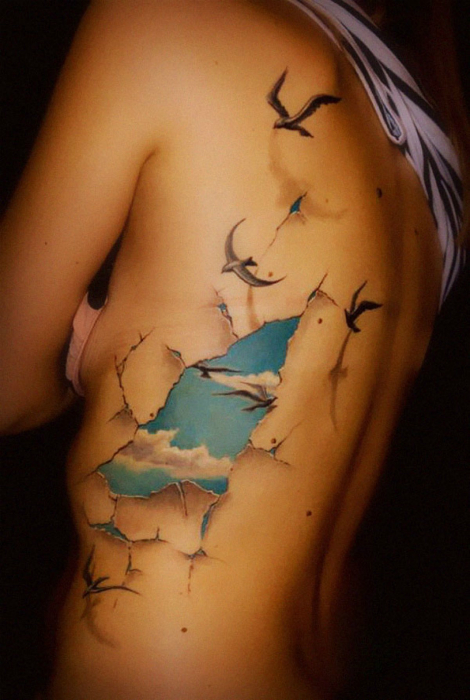 Фантастическая татуировка: сквозь разорванную человеческую плоть проглядывается голубое небо.