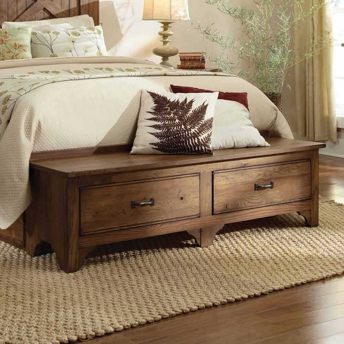 У изножья кровати разместилась деревянная тумбочка, которая стала удачной находкой для оформления спальни.