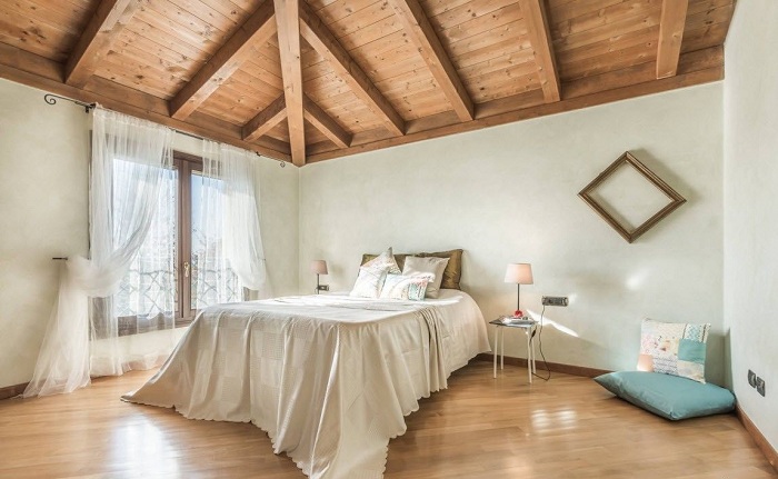 Оригинальный декор комнаты для сна с помощью деревянного потолка и милых белых штор.