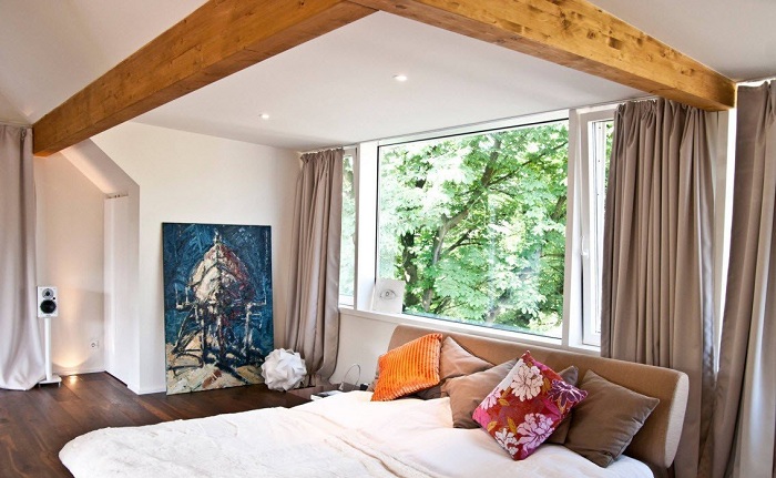 Удачный интерьер спальной с применением деревянных планок и шторами цвета кофе с молоком.
