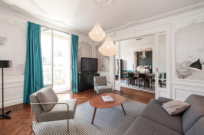 Серо-белая гостинная с бирюзовыми шторами, которые добавляют интерьеру комнаты ярких красок.