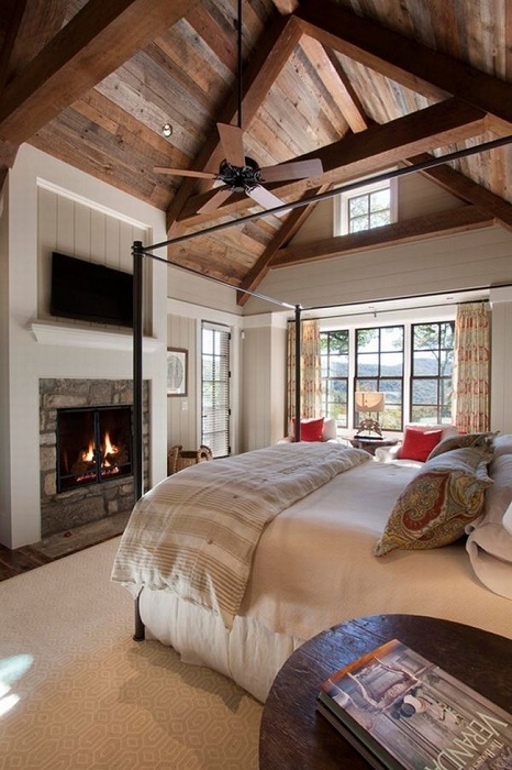 Шикарная спальня с камином и красивым деревянным потолком.