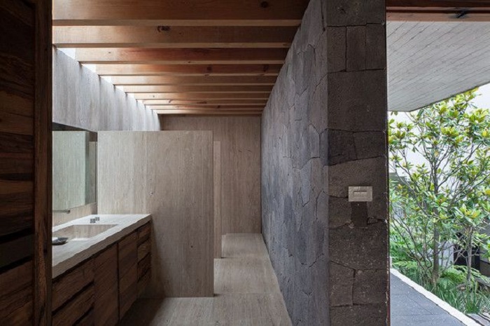 Необычная ванная с интересным интерьером, который подчеркивает скрытое освещение и каменная стена.
