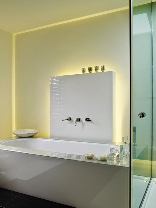 Необычный интерьер ванной в светлых тонах дополняет скрытое освещение.
