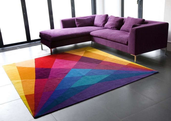 Сочетание симпатичного фиолетового дивана с ярким ковриком на полу - это прекрасная возможность создать интересный вариант интерьера.