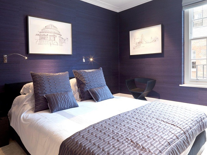Интересный интерьер спальни с темно-синими обоями, которые подчеркивают индивидуальность комнаты.