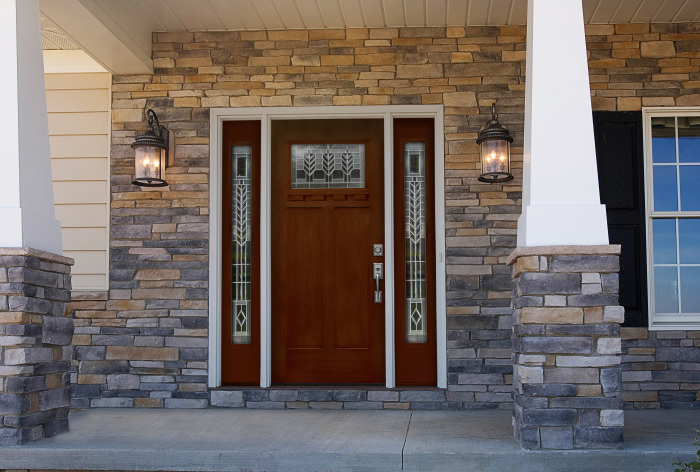 Входная дверь из дорогой породы древесины будет отлично сочетаться с каменной отделкой фасада. 