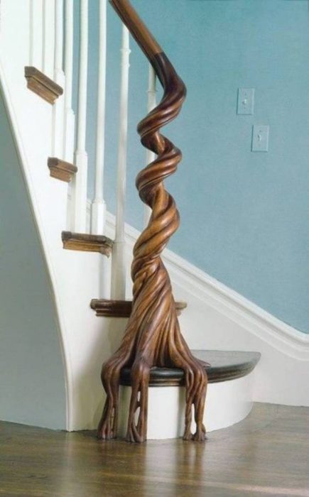 Декоративное дерево, плавно переходящее в перила деревянной лестницы.  