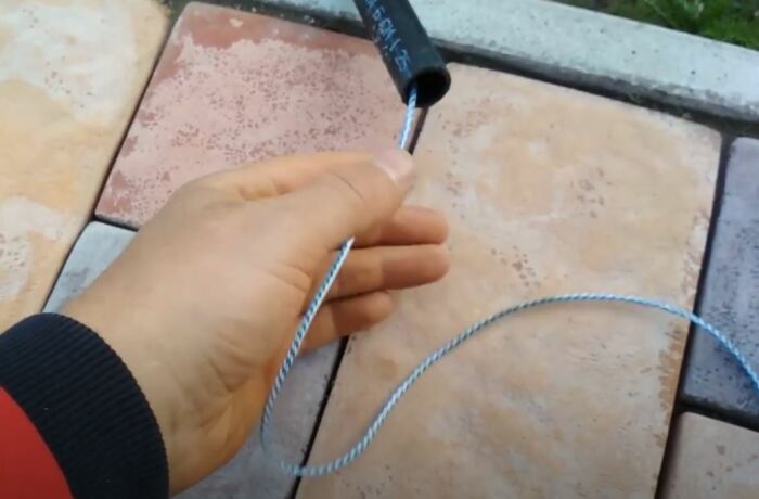 Просовываем веревку с пробкой. /Фото: youtube.com.