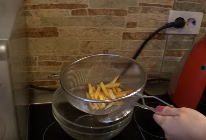 Выкладывайте картофель на дуршлаг, чтобы с него стекло лишнее масло.