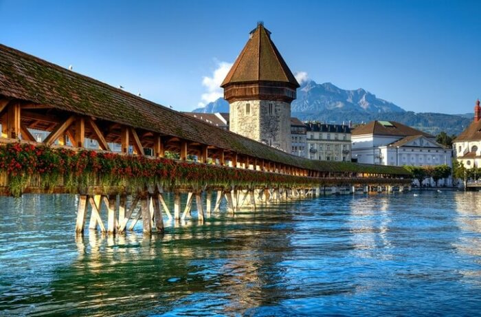 Зигзагообразный деревянный мост Капелльбрюкке, огибающий восьмигранную каменную башню, издревле является символом швейцарского города Люцерн. | Фото: myswitzerland.com.