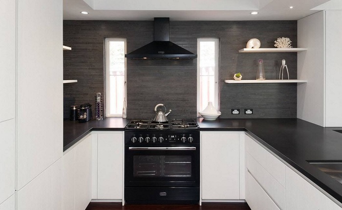 Интересное сочетание белоснежных поверхностей кухонных шкафов и черных глянцевых столешниц.