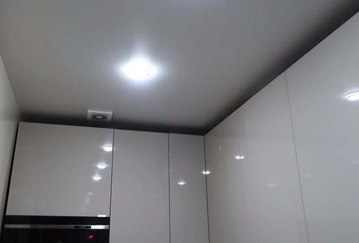 Глянцевые поверхности и грамотное освещение визуально увеличили пространство кухни-коридора. | Фото: youtube.com.