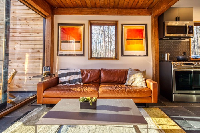 Уютная гостиная с кожаными диванами понравится тем, кто любит комфорт и уют в загородной резиденции (Catskills Cabin, Кэтскилл). | Фото: thebackcountryhutcompany.com.