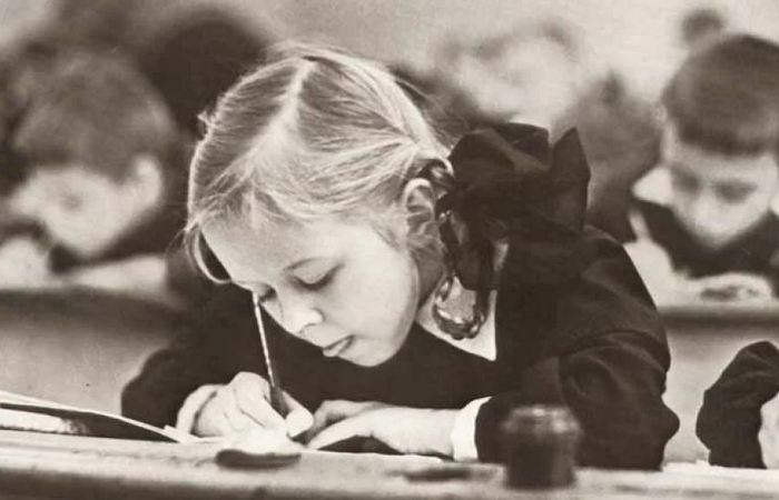 Советская школьница пишет перьевой ручкой (на переднем плане - чернильница на парте). /Фото: back-in-ussr.com